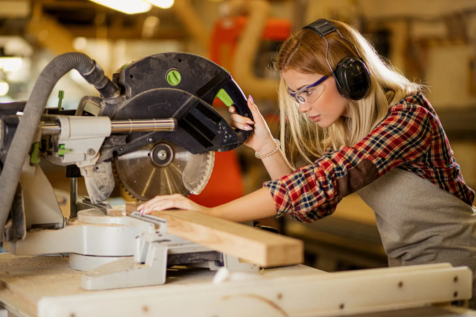 concentrated woman carpenter behind powerful electric machine, woman use circular sawer for wood cutting