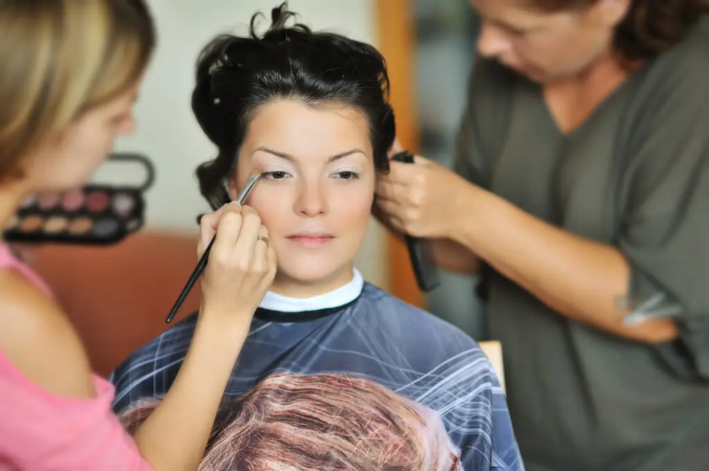 Young,Beautiful,Bride,Applying,Wedding,Make-up,By,Make-up,Artists