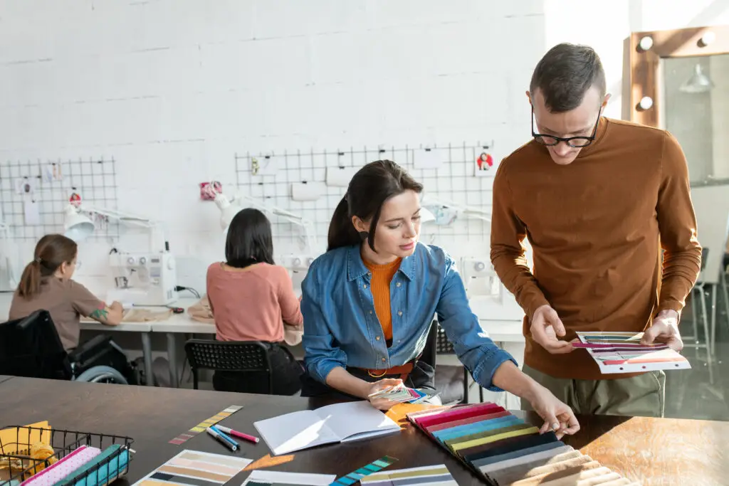 Two,Fashion,Designers,Working,Over,New,Collection,Against,Seamstresses