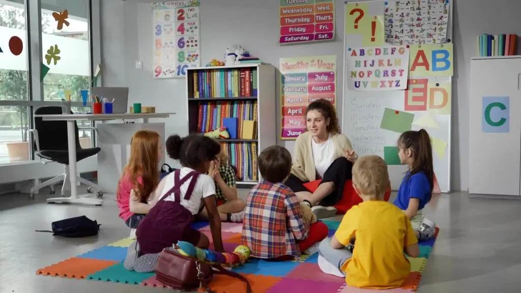 Small,Nursery,School,Children,With,Teacher,Sitting,On,Floor,Having