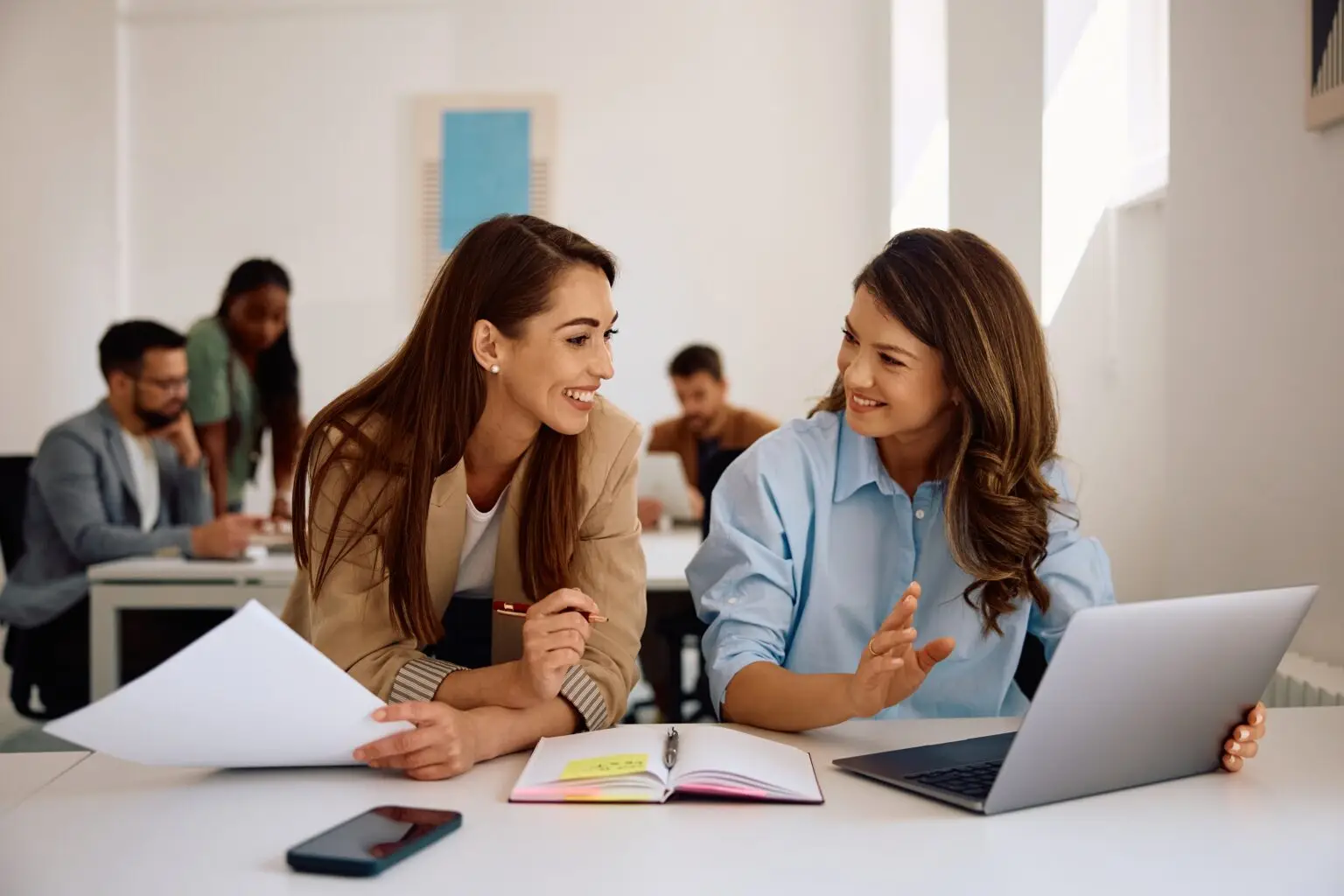 Happy,Businesswomen,Communicating,While,Using,Laptop,And,Working,In,Creative